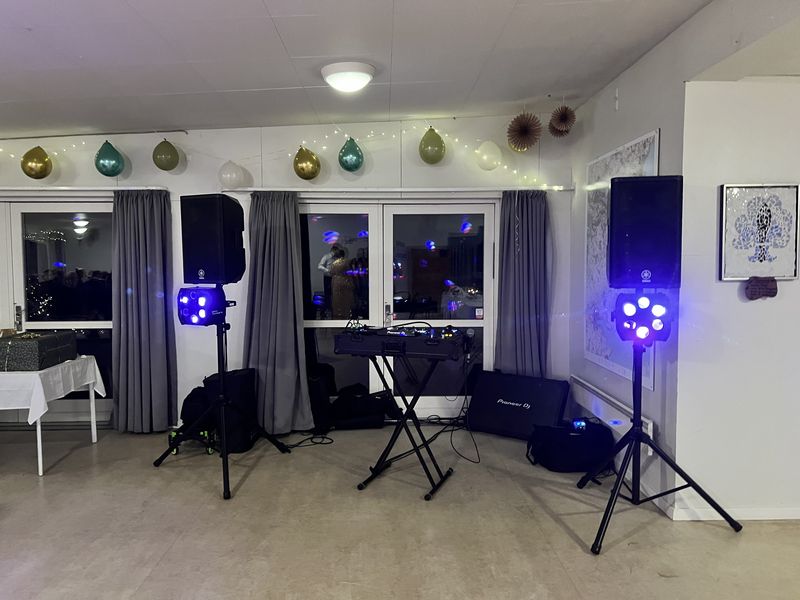 DJ-opstilling med blå lyseffekter i et selskabslokale pyntet med balloner