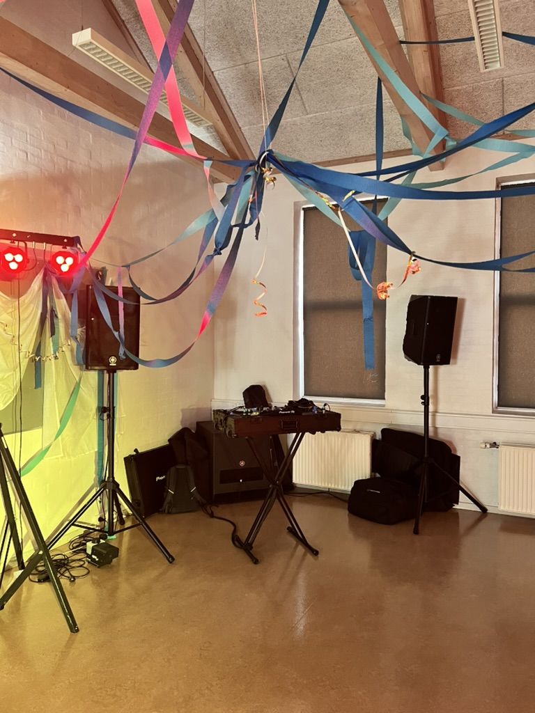 DJ-opstilling med røde lyseffekter under farverige serpentiner til en skolefest